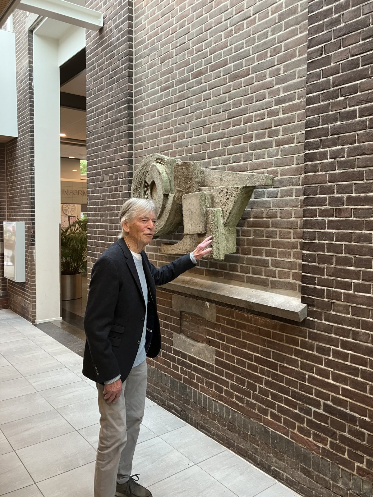 Harm de Noord wijst naar zijn reliëf in De Plataan